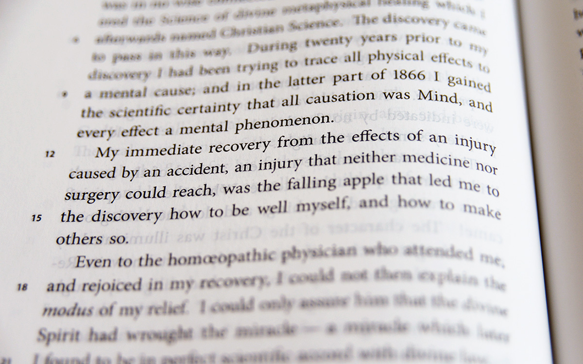 Image description: Photograph showing a close-up of Retrospection and Introspection, page 24. The text in focus reads: "My immediate recovery from the effects of an injury caused by an accident, an injury that neither medicine nor surgery could reach, was the falling apple that led me to the discovery how to be well myself, and how to make others so."