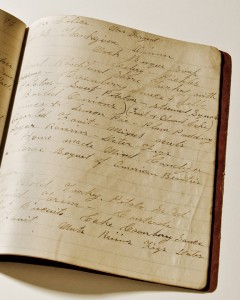 Image description: Color photo of a notebook with weathered pages, open to a page covered in slanted cursive writing. A header at the top of the page says "Thanksgiving Dinner."
