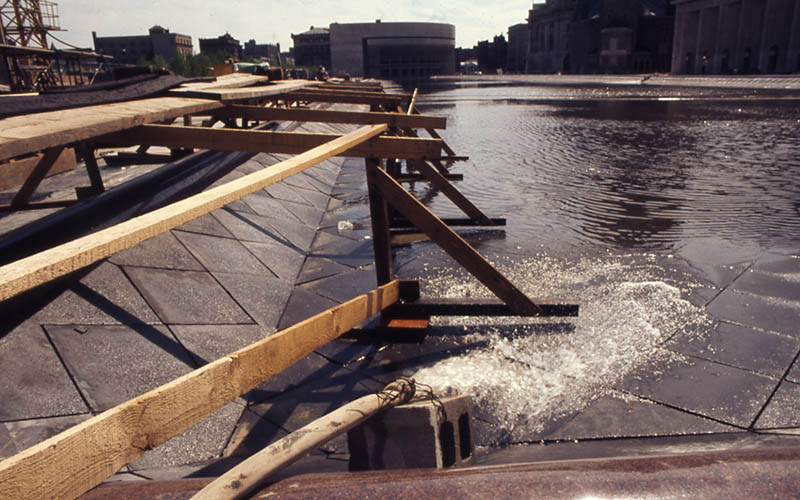 A hose pumps water into the reflecting pool, circa 1972