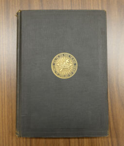 Image: Front cover of an antique concordance to Science and Health. The front cover is blank (dark brown) except for a golden seal