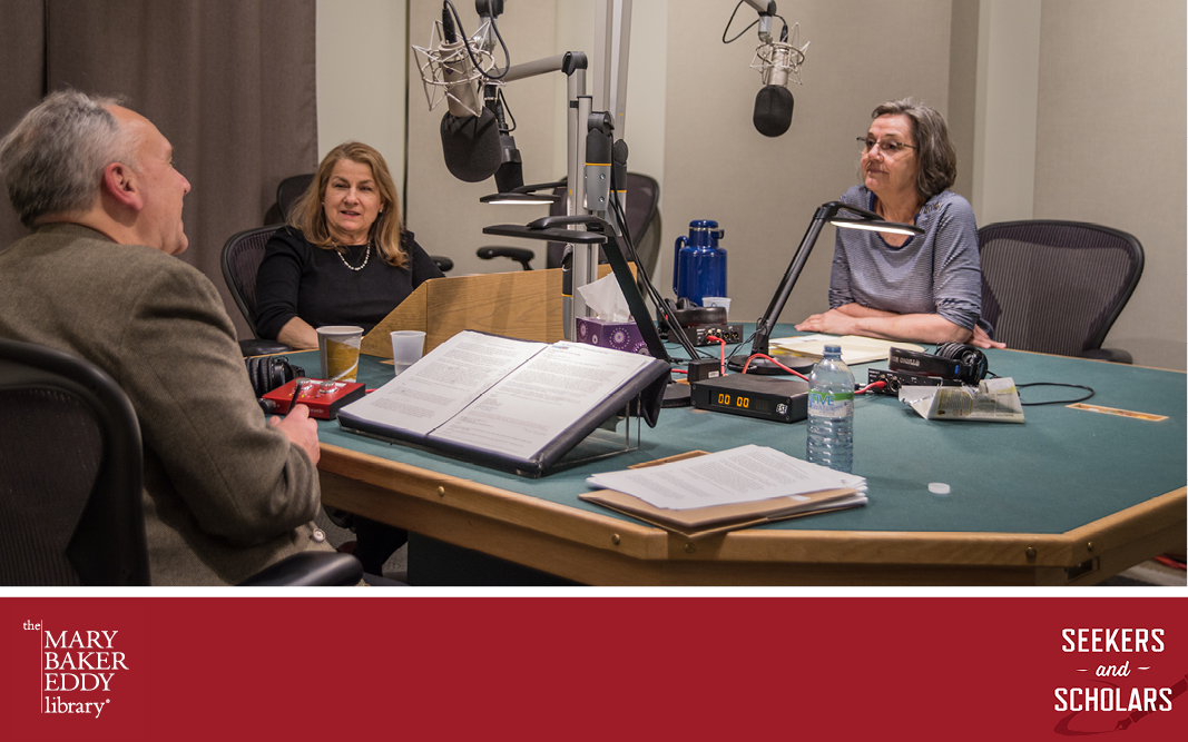 Image description: Photograph of three people sitting around a table in a recording studio (where Seekers and Scholars is recorded). Two women, episode guests Dr. Patricia Likos Ricci and Pam Winstead, and one man, host Jonathon Eder, are talking to each other. Microphones are suspended from a central metal frame in front of each of the three people.