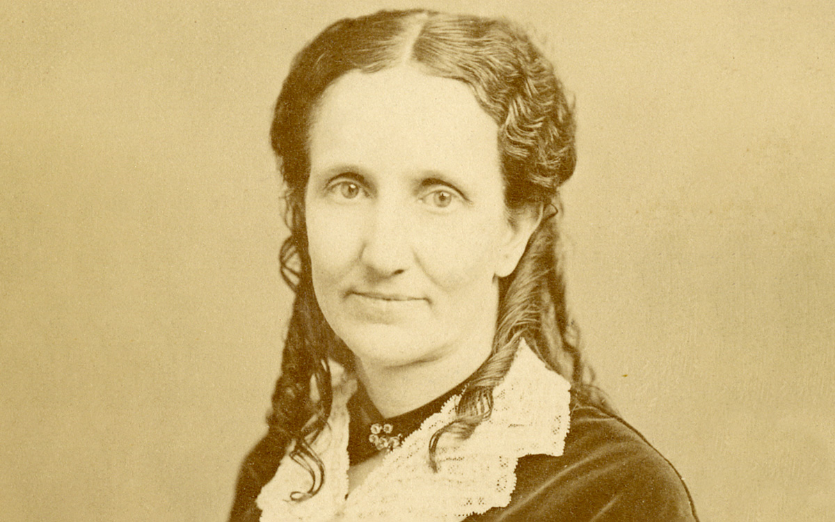 Image description: Sepia-toned portrait photograph of Mary Baker Eddy, with hair partially tied back and wearing a dark dress with a white lace collar.